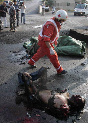 Quote A member of the Lebanese Red Cross walks past a badly burnt body in Beirut's port, which was targeted by Israeli warplanes, July 17 - Reuters Unquote