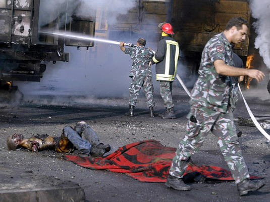 Quote Lebanese firefighters try to extinguish the fire while the dismembered and burnt corpses of two Lebanese civilians killed in an Israeli air raid lie on the ground at the port in Beirut Unquote